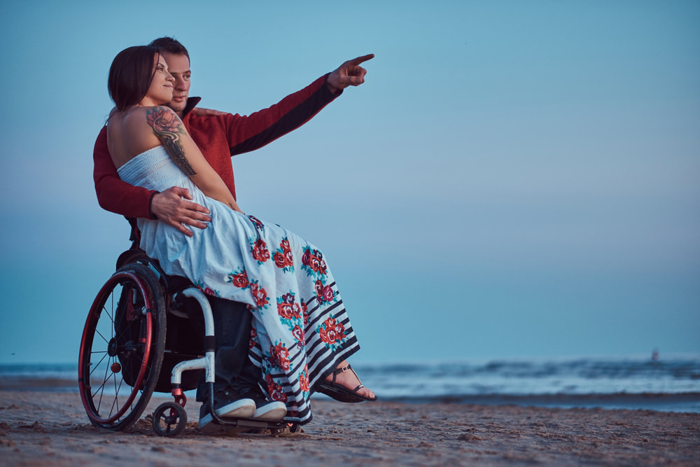 Man in wheelchair on the beach with girlfriend